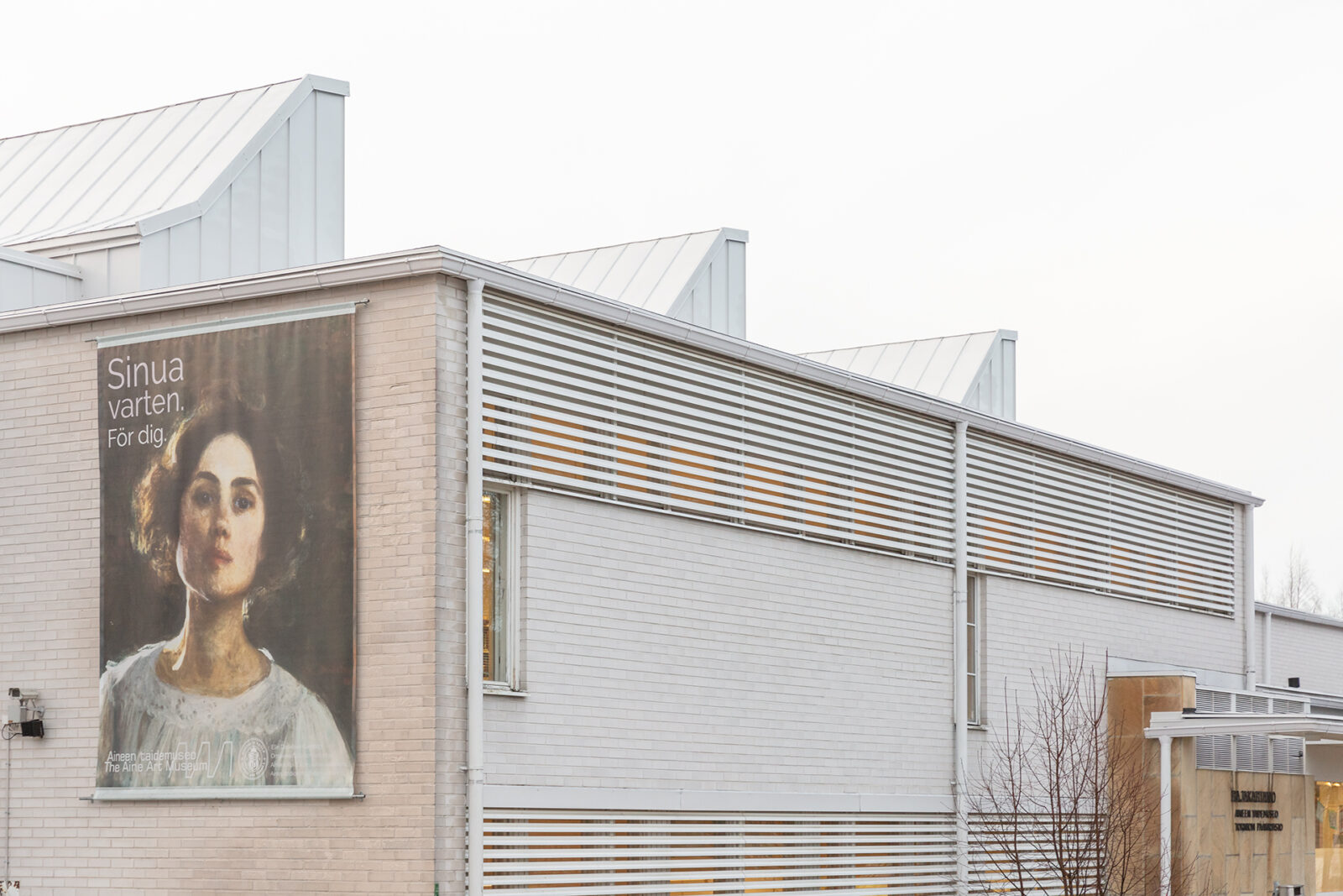 Valokuva museorakennuksen julkisivusta. Seinään on kiinnitetty suuri mainoslakana, jossa on taiteilija Elin Danielson-Gambogin omakuva ja teksti "Sinua varten. För dig."