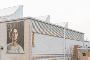 Valokuva museorakennuksen julkisivusta. Seinään on kiinnitetty suuri mainoslakana, jossa on taiteilija Elin Danielson-Gambogin omakuva ja teksti "Sinua varten. För dig."