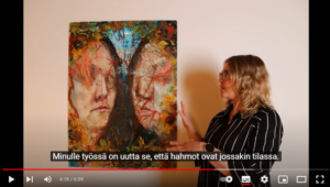 Pysäytyskuva Youtube-videosta. Kuvan vasemmassa reunassa on kaksia kasvoja esittävä värikäs maalaus ja oikeassa reunassa maalausta katsova ihminen.