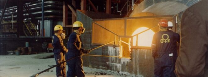 Kuvassa 3 miestä suojavarusteissa ottavat pitkävartisella välineellä näytettä rautasulaton sisältä.